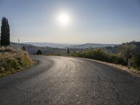 the road is curved so that a man can take this photo in the direction of the sun