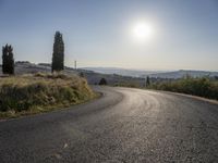 the road is curved so that a man can take this photo in the direction of the sun