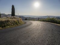 the road is curved so that a man can take this photo in the direction of the sun