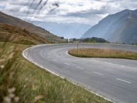 a motorcyclist rides down a curved roadway in the countryside of a valley