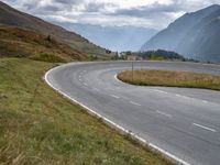 a motorcyclist rides down a curved roadway in the countryside of a valley