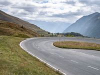 a motorcyclist rides down a curved roadway in the countryside of a valley