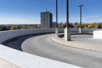 a curved roadway next to the ocean on a sunny day in canada and a building