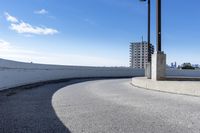 a curved roadway next to the ocean on a sunny day in canada and a building