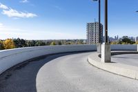 a curved roadway next to the ocean on a sunny day in canada and a building