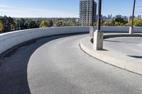 a curved roadway next to the ocean on a sunny day in canada and a building