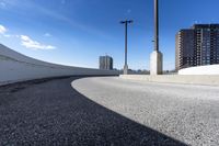 a curved roadway next to the ocean on a sunny day in canada and a building