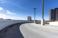 a curved roadway next to the ocean on a sunny day in canada and a building