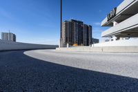 a curved roadway next to the ocean on a sunny day in canada and a building