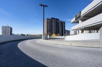 a curved roadway next to the ocean on a sunny day in canada and a building