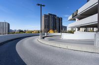 a curved roadway next to the ocean on a sunny day in canada and a building