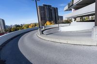 a curved roadway next to the ocean on a sunny day in canada and a building