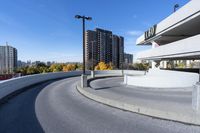 a curved roadway next to the ocean on a sunny day in canada and a building