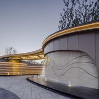 the building has a curved roof, and a water feature is designed like waves and waves