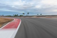 a photo of a dirt race track with sun setting in the distance of the track