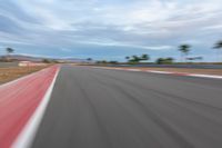 a photo of a dirt race track with sun setting in the distance of the track