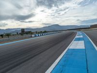 Curving Race Track: Asphalt Road with Clouds in the Background