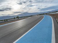 Curving Race Track: Asphalt Road with Clouds in the Background