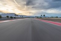 a photo of a dirt race track with sun setting in the distance of the track