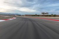 a photo of a dirt race track with sun setting in the distance of the track