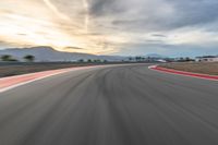 a photo of a dirt race track with sun setting in the distance of the track