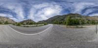 a wide road with several lanes and hills in the background, and trees and brush