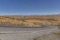 a road curves around a curve with mountains in the distance and no parking sign or sign on it