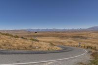 a road curves around a curve with mountains in the distance and no parking sign or sign on it