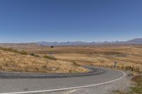 a road curves around a curve with mountains in the distance and no parking sign or sign on it