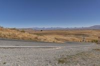 a road curves around a curve with mountains in the distance and no parking sign or sign on it