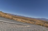 a road curves around a curve with mountains in the distance and no parking sign or sign on it