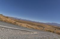 a road curves around a curve with mountains in the distance and no parking sign or sign on it