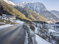 the road curves over snow and snowy mountains as the sun sets on it's horizon