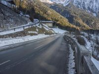 the road curves over snow and snowy mountains as the sun sets on it's horizon