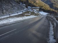 the road curves over snow and snowy mountains as the sun sets on it's horizon