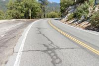 a road curves down the side of a rocky mountain with some trees on the far side