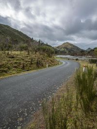 a road leading through an area with a lot of mountains in the background, and a highway is running through the field