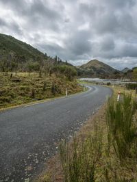 a road leading through an area with a lot of mountains in the background, and a highway is running through the field