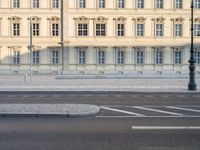 man on bicycle rides down street in front of building with arched windows and white trim