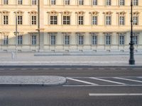 man on bicycle rides down street in front of building with arched windows and white trim