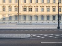 man on bicycle rides down street in front of building with arched windows and white trim