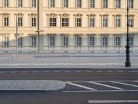 man on bicycle rides down street in front of building with arched windows and white trim