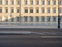 man on bicycle rides down street in front of building with arched windows and white trim