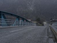 a person on a bike crosses a bridge in mountainside town in the background,