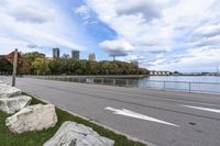 a person on a bicycle rides past a river in the city park near a fenced area