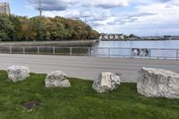 a person on a bicycle rides past a river in the city park near a fenced area