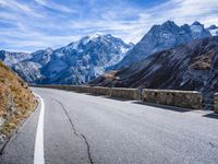 a man riding down the road on his bike past mountains in the background and clouds overhead