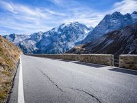 a man riding down the road on his bike past mountains in the background and clouds overhead