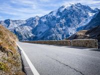 a man riding down the road on his bike past mountains in the background and clouds overhead