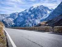 a man riding down the road on his bike past mountains in the background and clouds overhead